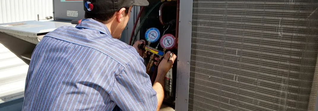 HVAC technician servicing a condenser unit in Shelbyville